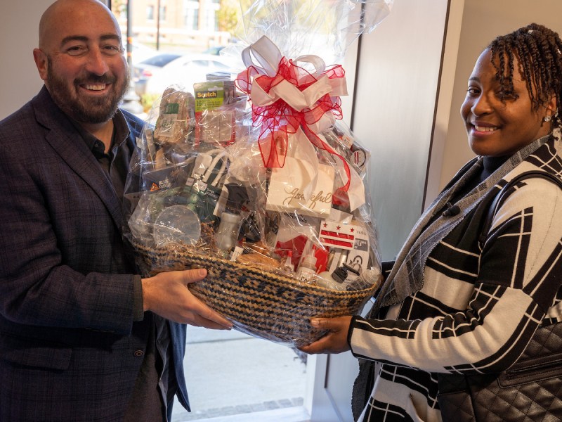 John Falcicchio, D.C. Deputy Mayor for Planning and Economic Development, presents Brittany Freeman with a congratulatory gift basket after she closed on her new home in southeast D.C. (Marckell Williams/The Washington Informer)