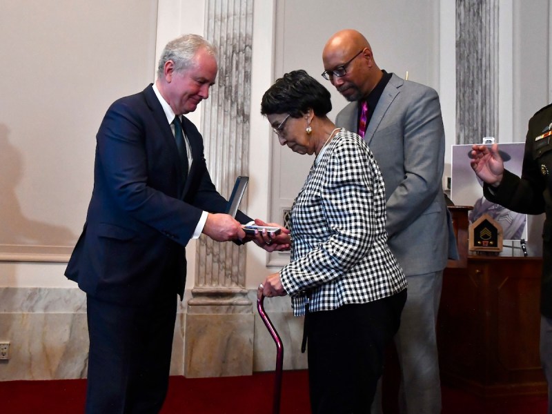 From left: Sen. Chris Van Hollen (D-Md.) presents the Distinguished Service Cross to Joann Woodson, widow of Staff Sgt. Waverly Woodson, and their son Stephen Woodson. Staff Sgt. Woodson is credited with saving more than 200 lives during the invasion of Omaha Beach on D-Day. (Robert R. Roberts/The Washington Informer)