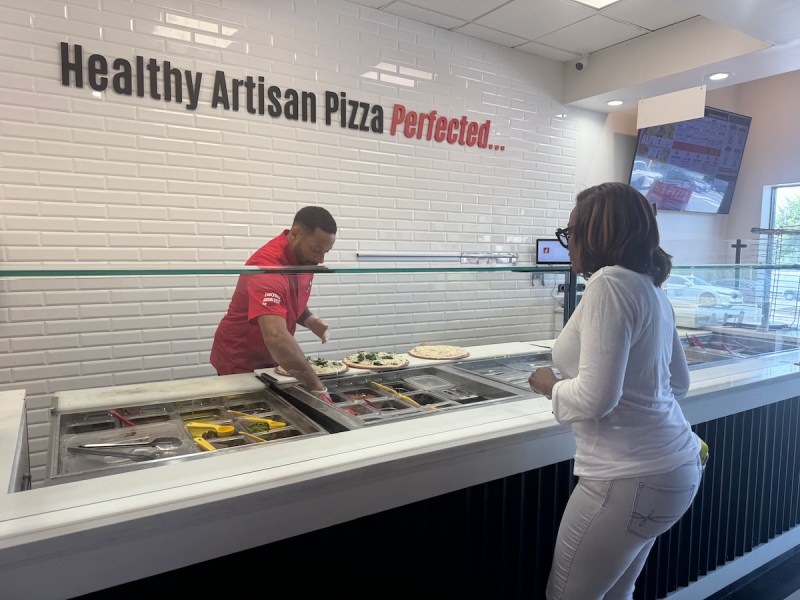 BurnBox, a Black-owned pizza shop with locations in Largo and Waldorf, gave away free slices for families on Aug. 26 for the new school year. Owner Ryan Whitfield (pictured with a customer) is planning a future holiday giveaway to help those in need, and prides himself on his support for the community as much as for the quality of his pizzas. (Anthony Tilghman/The Washington Informer)