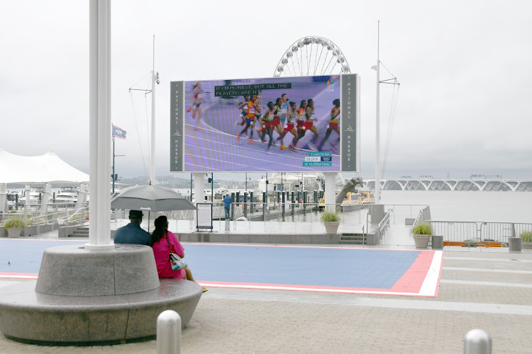 Even in the rainfall of the past weekend, interested fans tuned into the track and field portion of the Olympics on a large screen at the National Harbor in Oxon Hill, Maryland, to cheer on local talents such as Noah Lyles and Quincy Wilson. (Anthony Tilghman/The Washington Informer)