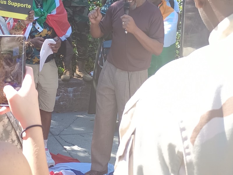 Rafiki Morris of the All-African People's Revolutionary Party stood atop the French and British flags while providing comments in front of the French Embassy in Washington, D.C., during the "No War in Niger" rally on Sept. 2. (Sam P.K. Collins/The Washington Informer)