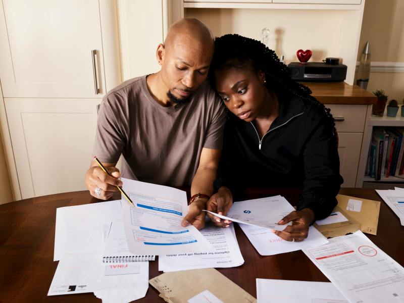 couple sitting by table looking through bills