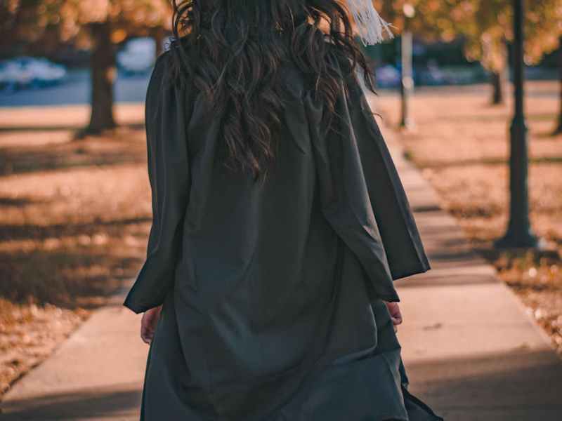 woman in black long sleeve dress standing on brown concrete pathway