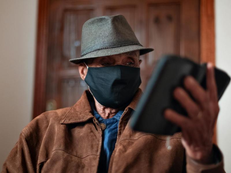 aged man in protective mask with smartphone